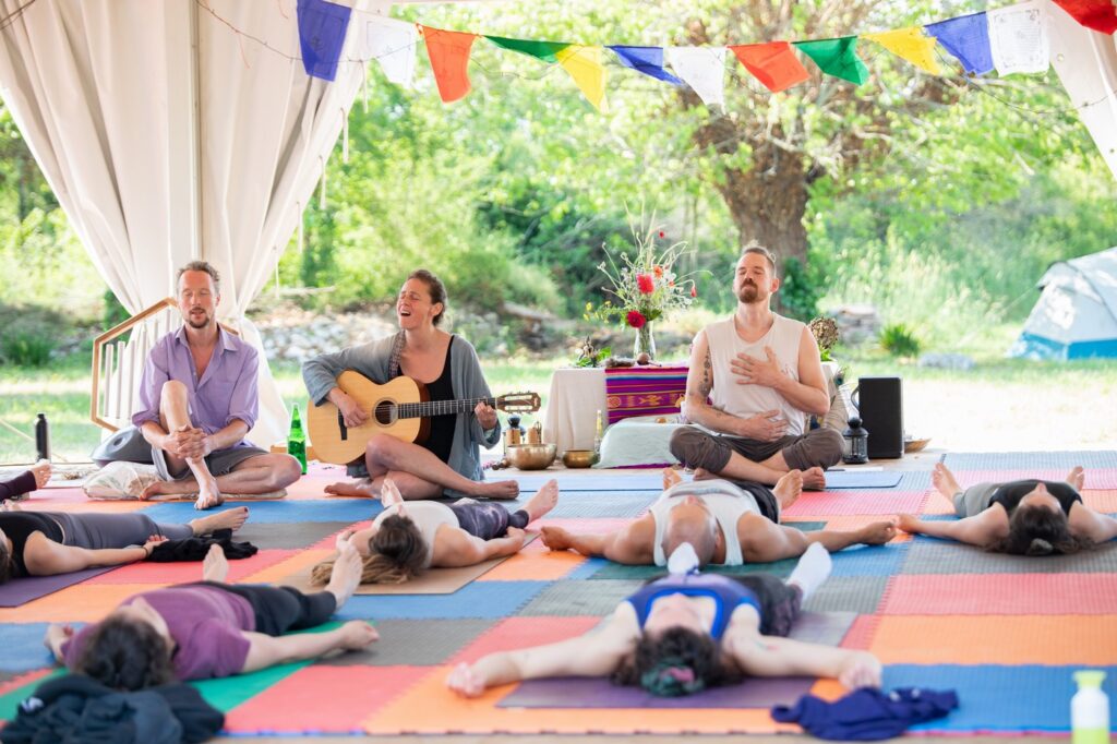 Morning yoga class with two musicians playing live music in a colourful environment.