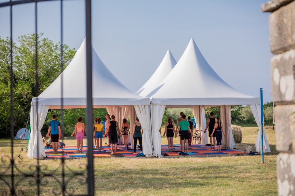 People practicing Yoga in a big white tent in beautiful environment in Croatia.