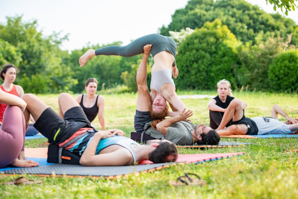 People practicing partner stetches in the garden during AcroYoga retreat in Slovenia.