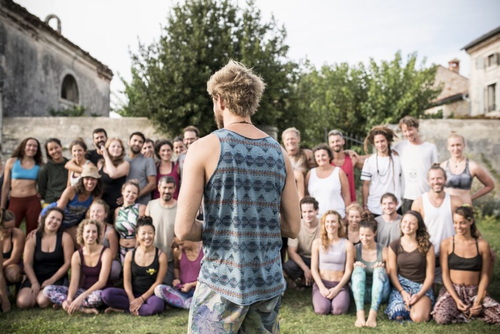 Person facing the back to the camera with a big group of people in the background preparing for a group photo during the AcroYoga retreat in Croatia.
