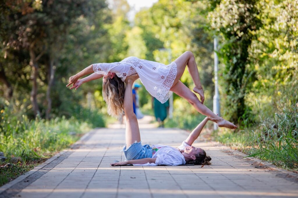 Beautiful AcroYoga pose of one girl being on the ground and another one flying ontop in a position called high flying whale in beautiful Croatia.