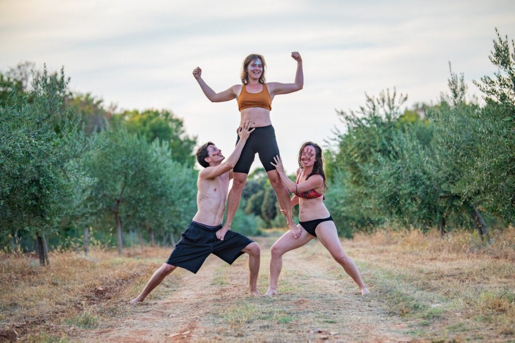 two people holding another one up into the air who is posing. all having fun and smiling in between olives grooves in croatia.