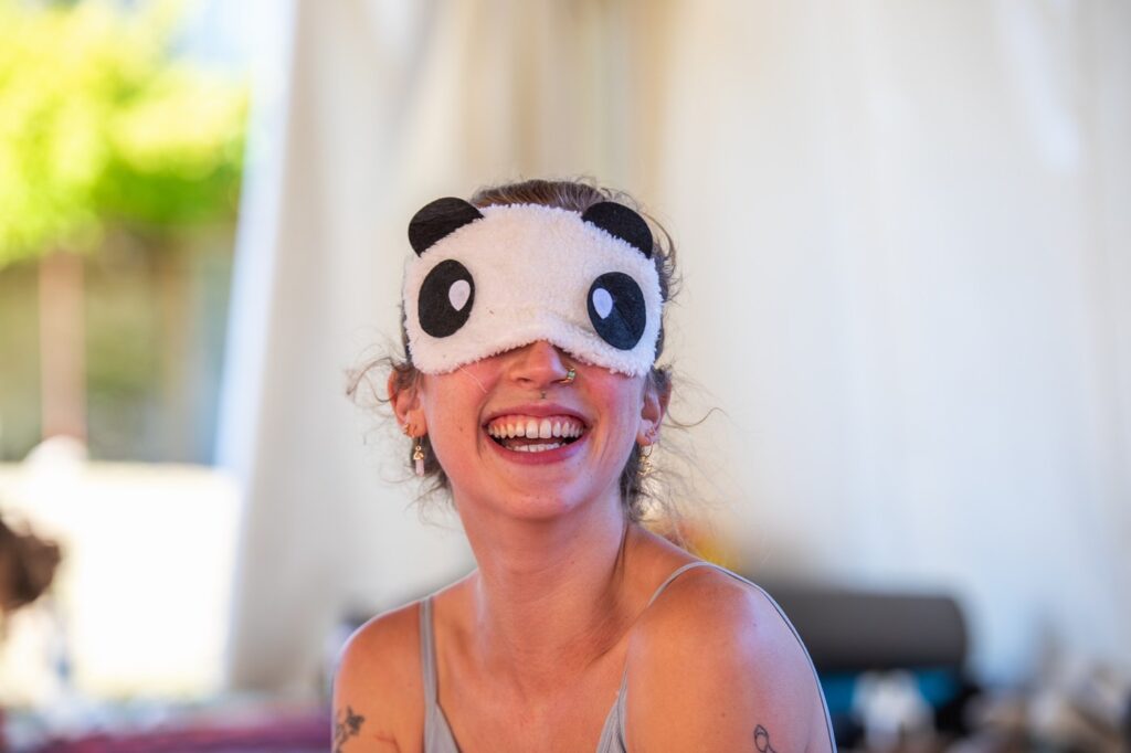 Girl wearing a panda blindfold and smiling towards the camera during our AcroYoga warmup games in Croatia.
