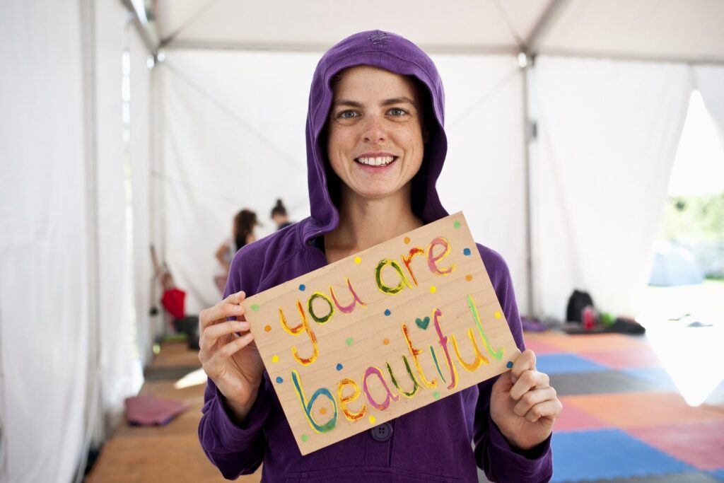 Girl holding a sign saying you are beautiful. Good vibes at our barefootyoga retreats.