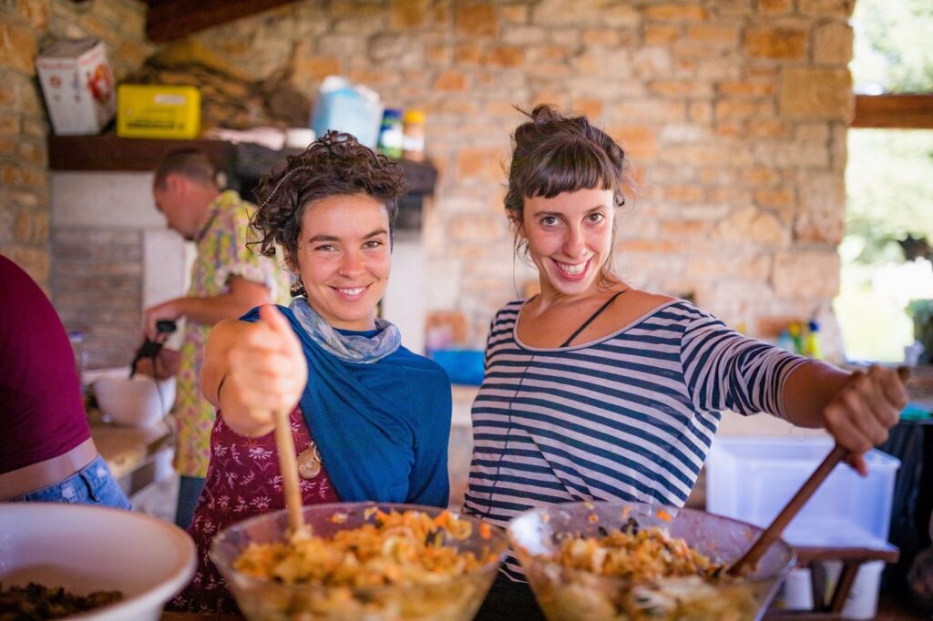 Two girls cooking and smiling in our outdoo kitchen in Croatia.