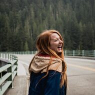 Girl on a bridge nearby a forest laughing.
