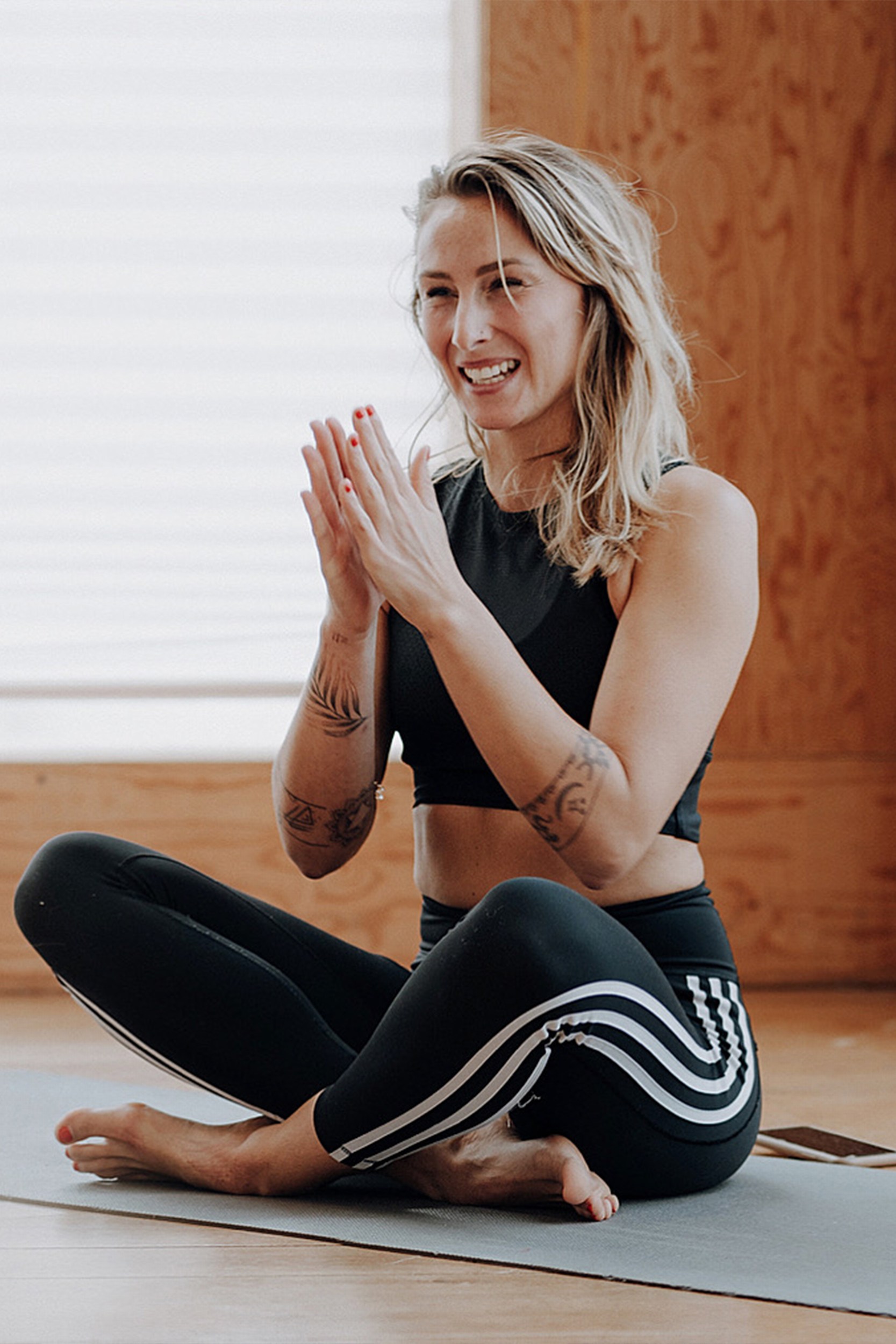 Girl holding her hands in namaste during a yoga class and smiling.