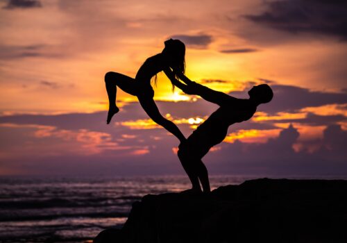 Silhouette of a couple doing AcroYoga in the sunset.