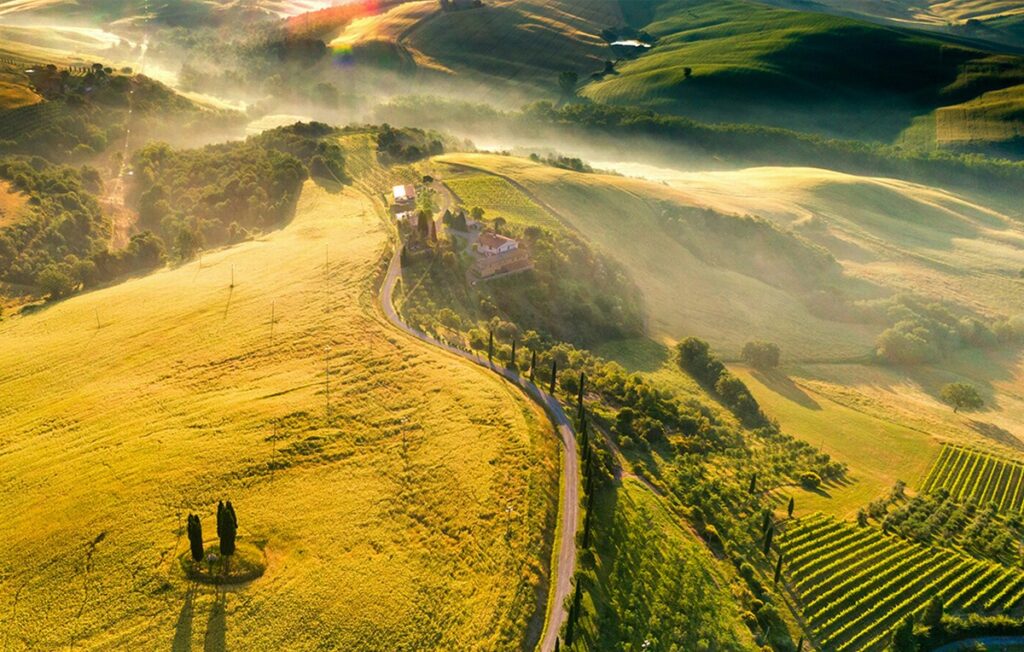 Drone image of mist over the Tuscany hills from above during sunrise.