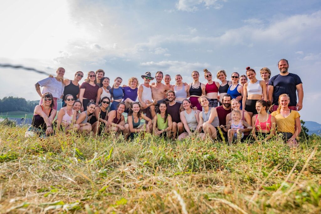 A group picture of about 30 people, smiling into the camera on a sunny day with clouds in the background.